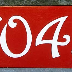May include: A red house number sign with white cursive numbers 7045.