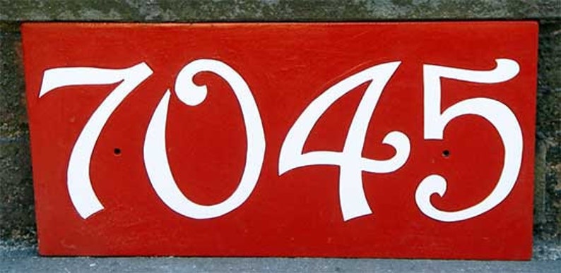 May include: A red house number sign with white cursive numbers 7045.