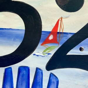 May include: A hand-painted house number sign with the number "32" in black paint. The background is a blue and white seascape with a red sailboat.
