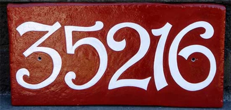 May include: A red house number plaque with white cursive numbers reading "35216".