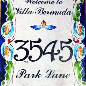 May include: A decorative tile sign with a blue and white floral border. The sign says "Welcome to Villa Bermuda" and "3545 Park Lane".