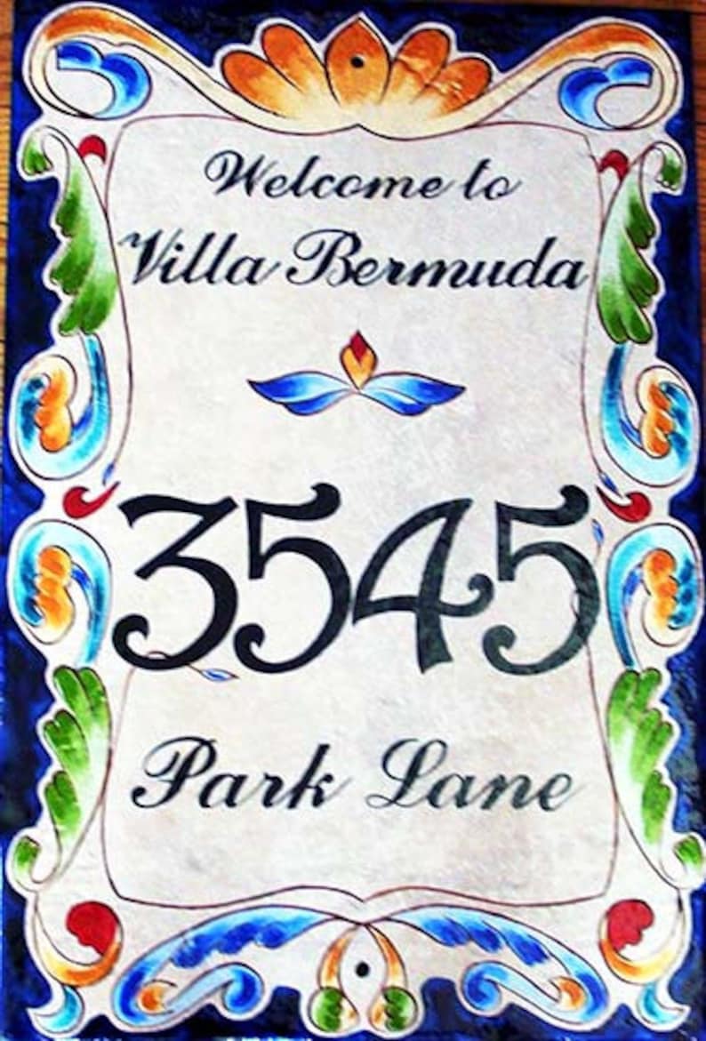 May include: A decorative tile sign with a blue and white floral border. The sign says "Welcome to Villa Bermuda" and "3545 Park Lane".