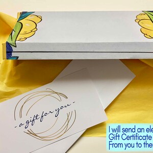 May include: A white gift certificate with gold lettering that says "a gift for you" inside a white box with a lemon design. The box is wrapped in yellow tissue paper.