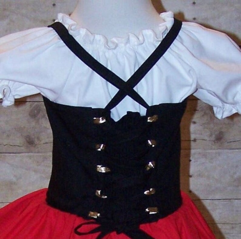 Pu&ograve; includere: Un corpetto nero con dettagli dorati e una blusa bianca con scollo a volant. Il corpetto ha una chiusura con lacci sul retro e viene indossato sopra una gonna rossa.