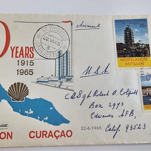 May include: Vintage envelope commemorating 50 years of Shell on Curaçao, 1915-1965. Features a map of Curaçao, a seashell, and stamps from the Netherlands Antilles. Includes handwritten address and postmark.