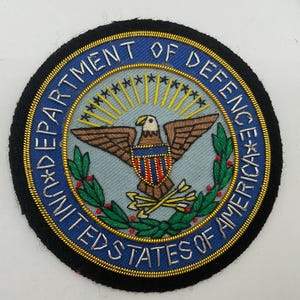Handgemaakte blazerpatch van gouddraad met het zegel van het Amerikaanse Ministerie van Defensie (fout, bijzonderheid).