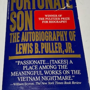 May include: A hardcover book titled "Fortunate Son" with gold lettering on a blue background. The book is "The Autobiography of Lewis B. Puller, Jr." and won the Pulitzer Prize for Biography. A quote from William Styron is also visible.