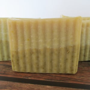 May include: Three bars of handmade soap with a light green and beige color. The soap has a rippled texture.