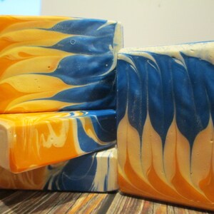 May include: Four bars of handmade soap with a marbled design in shades of orange, white, and blue.