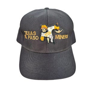 May include: Black baseball cap with an orange embroidered logo of a cartoon miner holding a pickaxe. The logo says "Texas El Paso Miners".