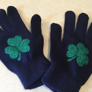 May include: A pair of navy blue knit gloves with green glitter shamrock designs.