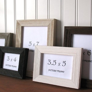 May include: A collection of five rectangular picture frames in varying colors including black, white, gray, and brown. Each frame features a textured, ribbed border and contains a white insert with printed dimensions of 3x4, 4x6, 5x7, and 3.5x5 inches.