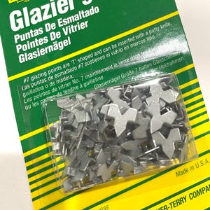 May include: A package of 50 silver-colored #7 glazing points for holding glass in place. The package is green and yellow and says "Glazier's Points" in large letters. The text on the package is in English, Spanish, French, and German. The package is made in the USA.