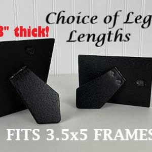 May include: Two black picture frame stands, each with a different leg length. The stands are 1/8" thick and fit 3.5x5 frames. "Choice of Leg Lengths" is written above the stands.