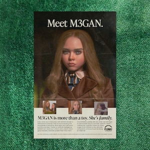 以下が含まれることがあります： M3GANという新しい人形のポスター。ポスターには、人形の写真が掲載されており、リアルな見た目の女の子で、長い茶色の髪と青い目をしています。ポスターのテキストには、「Meet M3GAN.」と「M3GAN is more than a toy. She's family.」と書かれています。