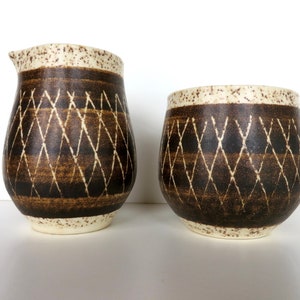 May include: A set of two brown and white ceramic creamer and sugar containers with a diamond pattern.