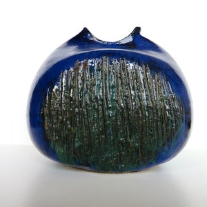 May include: A blue and green ceramic vase with a textured surface. The vase has a wide, round body and a narrow opening.