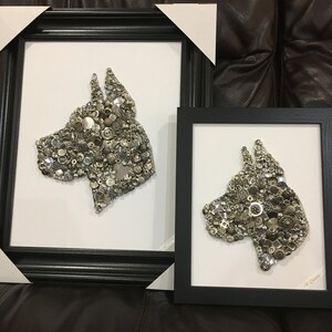 May include: Two framed black and white dog portraits made of buttons and other small metal objects. The larger portrait is on the left and the smaller portrait is on the right.