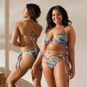 May include: Two women wearing colourful bikini tops and bottoms with a cartoon graphic print. The bikini tops are triangle shaped and the bottoms are tie-side.