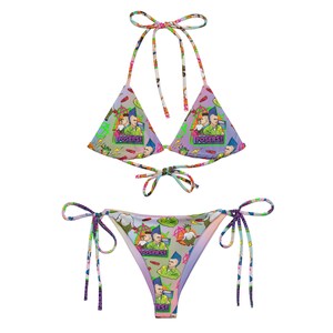May include: A colourful bikini with a tie-side bottom and a triangle top. The bikini is printed with a pattern of cartoon characters and the word "Posers!" repeated throughout.