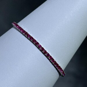 Può includere: Un braccialetto d'argento con una fila di piccole pietre preziose rosa brillante.