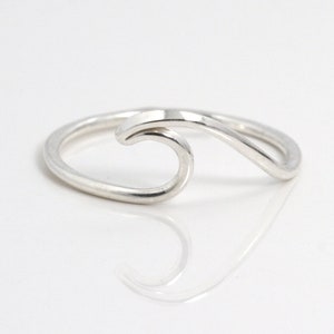 May include: A silver wave ring. The ring is made of a single piece of wire that is bent into the shape of a wave.