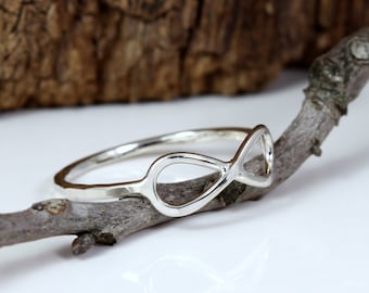 May include: A silver infinity ring with a smooth, polished finish. The ring is sitting on a branch.