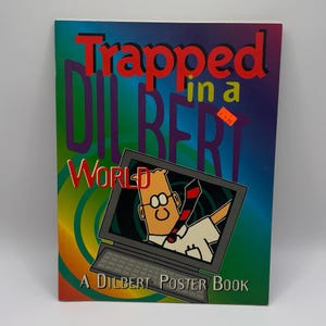 May include: A "Trapped in a Dilbert World" poster book. The cover features the title in red and purple, with a cartoon Dilbert character inside a laptop screen. The background has a gradient of green, blue, and orange.