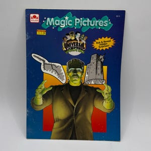 May include: A vintage "Magic Pictures" book featuring Universal Monsters. The cover has a blue background with the title in green and a picture of Frankenstein's monster. The book promises "Rub & Reveal Hidden Surprises!"