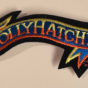 May include: A black fabric patch with a yellow, orange, and blue embroidered banner that reads "Molly Hatchet".
