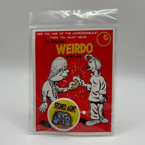 Op de afbeelding: Een rode en gele "Weirdo Badge" sticker in een doorzichtige plastic hoes. De sticker toont cartoonfiguren en de tekst "ARE YOU ONE OF THE UNDESIRABLES? ...THEN YOU MUST WEAR WEIRDO BADGE!" en "STONED AGIN!"