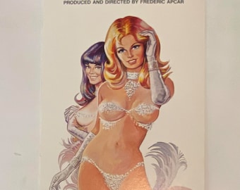 May include: A vintage advertisement for the Casino de Paris show at the Dunes Hotel and Country Club in Las Vegas. The ad features two women in glamorous costumes, with the text "The Most Lavish French Spectacular Ever Presented In Las Vegas!" and "Produced and Directed by Frederic Apcar."