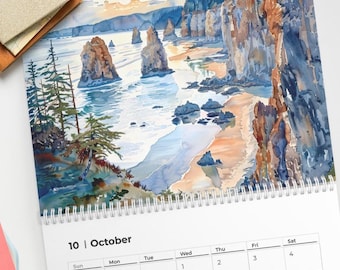 May include: A spiral-bound calendar open to October, featuring a watercolor painting of a coastal landscape with rock formations and a beach. The calendar includes a weekly grid with dates and days of the week.