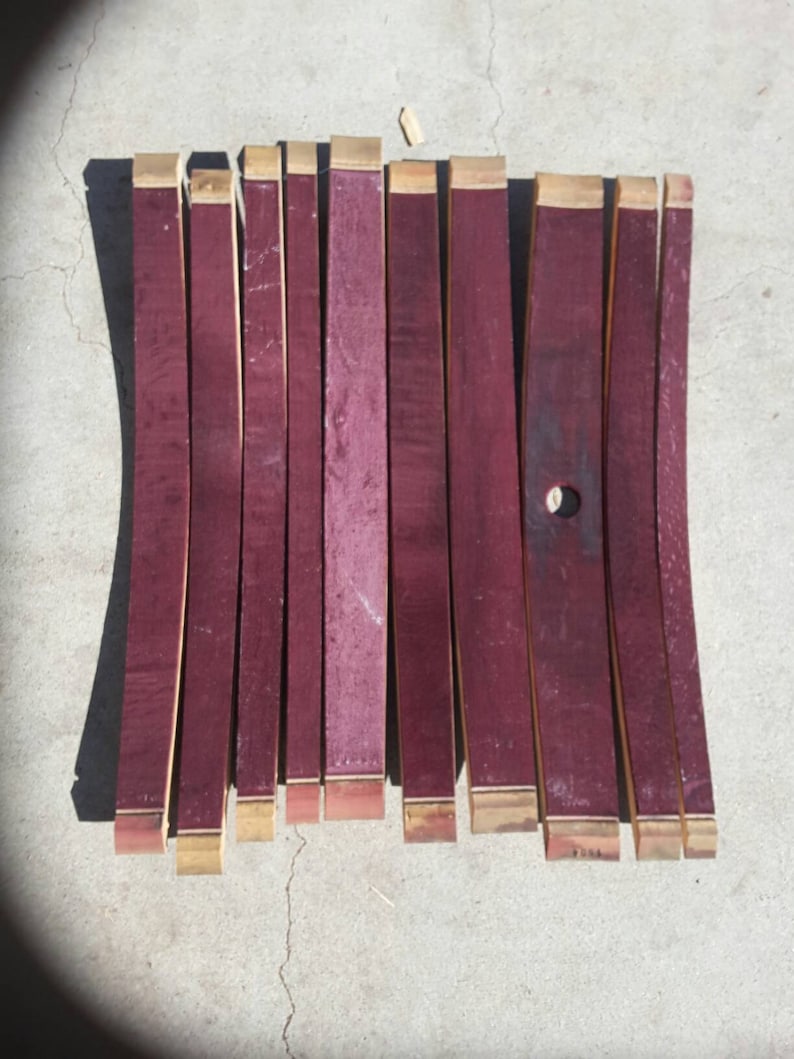 May include: Ten pieces of reclaimed wine barrel wood, each approximately 30 cm long and 5 cm wide. The wood is a deep burgundy red colour with a natural wood grain. The ends of the wood are trimmed with a thin strip of natural wood.