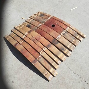May include: A set of wooden barrel staves, arranged in a curved shape, with a small hole in the centre. The staves are a mix of light and dark brown wood, with some showing signs of wear and tear.