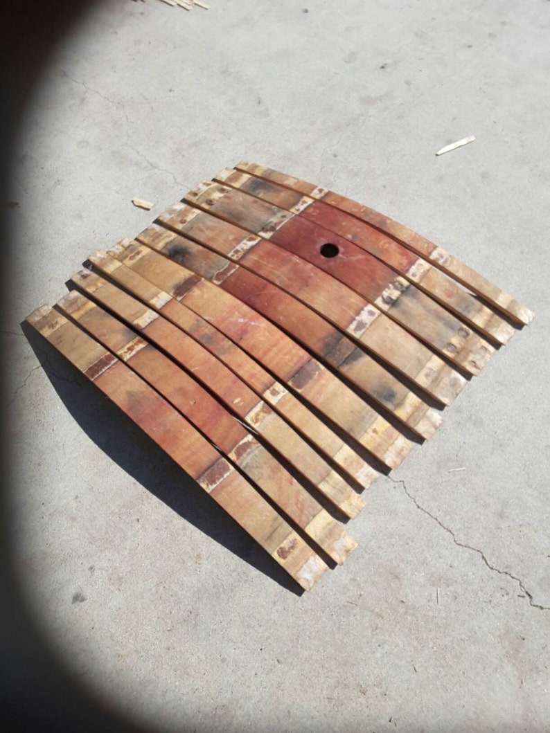 May include: A set of wooden barrel staves, arranged in a curved shape, with a small hole in the centre. The staves are a mix of light and dark brown wood, with some showing signs of wear and tear.