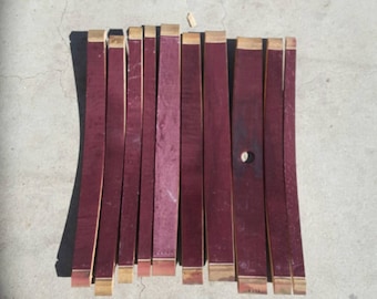 May include: A set of 12 wine barrel staves, each approximately 18 inches long, with a reddish-brown color and a natural wood finish. The staves are arranged in a row on a concrete surface.