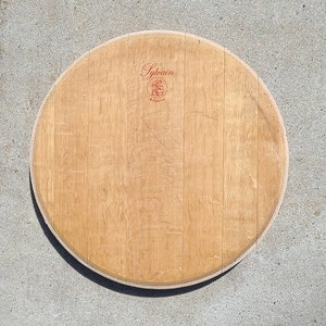 May include: A round wooden wine barrel head with a red label that says "Sylvain Reserve".