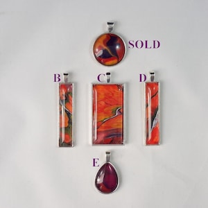 May include: Five pendants with abstract art designs. The pendants are made of silver and have a variety of shapes, including round, rectangular, and teardrop. The art designs are in shades of red, orange, yellow, and black. One pendant is marked "SOLD".