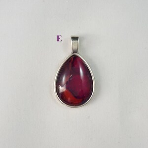May include: A teardrop-shaped pendant with a silver setting and a red and orange glass inlay.