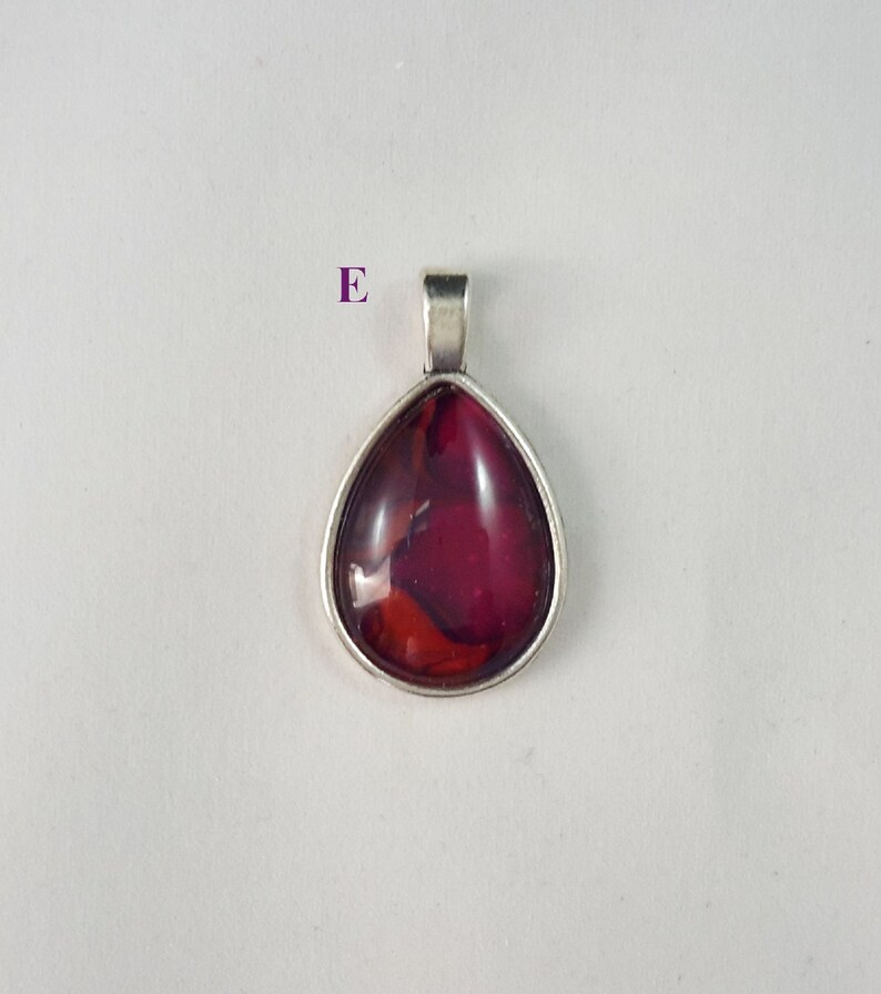 May include: A teardrop-shaped pendant with a silver setting and a red and orange glass inlay.