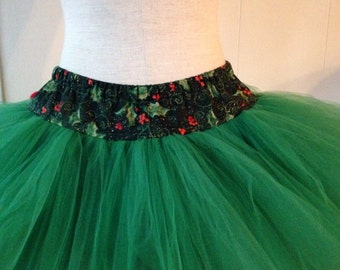 May include: A green tulle tutu skirt with a holly and berry print waistband.