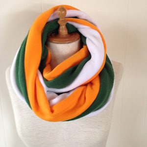 May include: A white, orange, and green infinity scarf made of fleece.