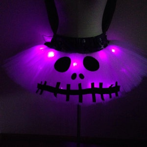May include: A white tulle tutu with a black Jack Skellington face design and purple LED lights.