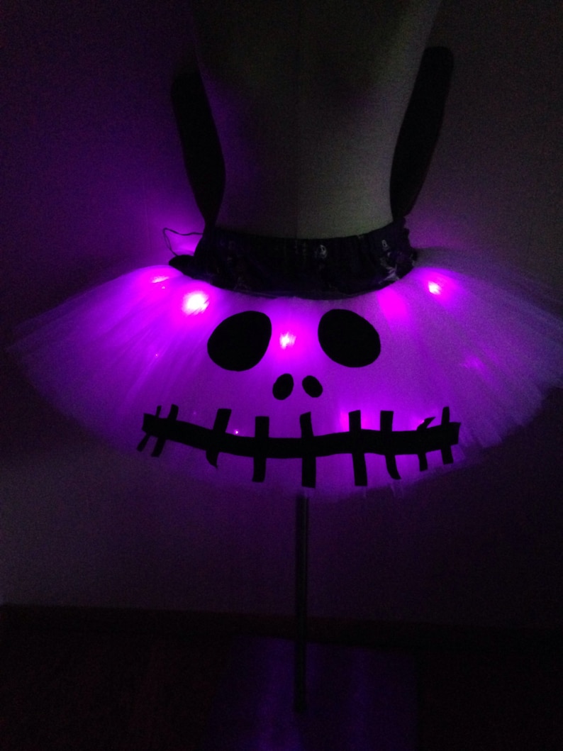 May include: A white tulle tutu with a black Jack Skellington face design and purple LED lights.