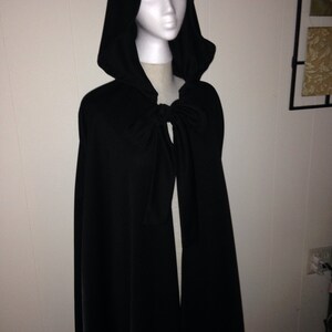 May include: A black hooded cape with a tie at the neck. The cape is made of a soft, flowing fabric.
