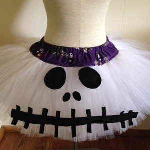 May include: White tulle tutu skirt with a black and white Jack Skellington face design. The waistband is purple with a black and white print.