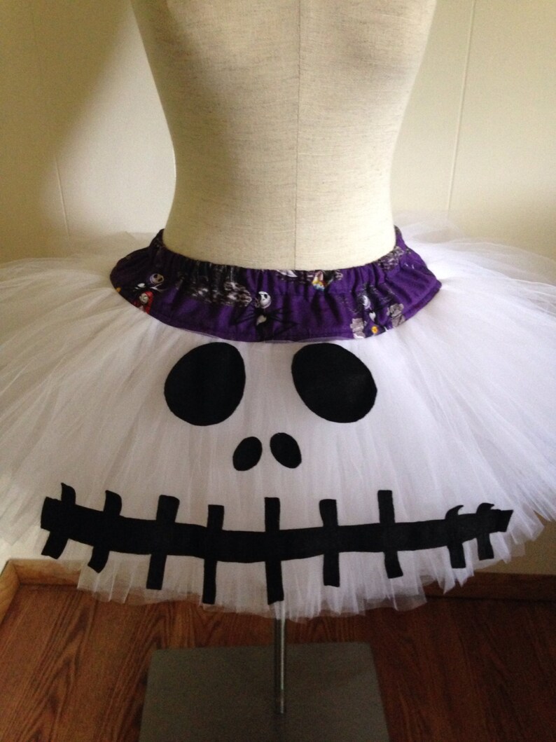 May include: White tulle tutu skirt with a black and white Jack Skellington face design. The waistband is purple with a black and white print.