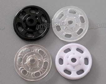 May include: Four sew-on snap fasteners, two clear and two white. The fasteners are circular in shape with multiple holes around the edge.