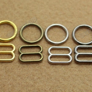 Puede incluir: Surtido de anillos y anillos en D de metal en acabados dorado, bronce y plateado. Los anillos son de varios tamaños y se utilizan comúnmente para manualidades, fabricación de joyas y accesorios de moda.